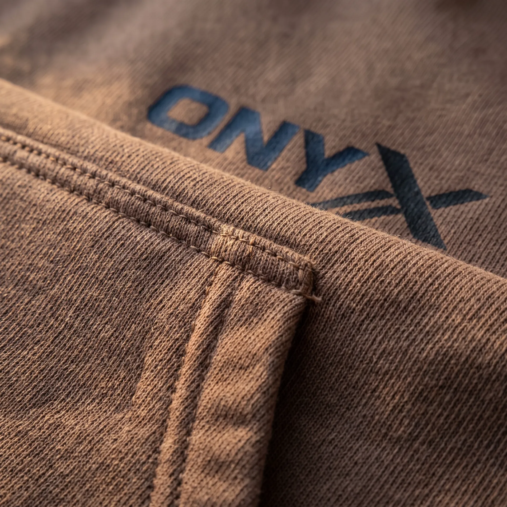 Macro detail of fabric, stitching and logo on the Heavyweight Pullover Hoodie