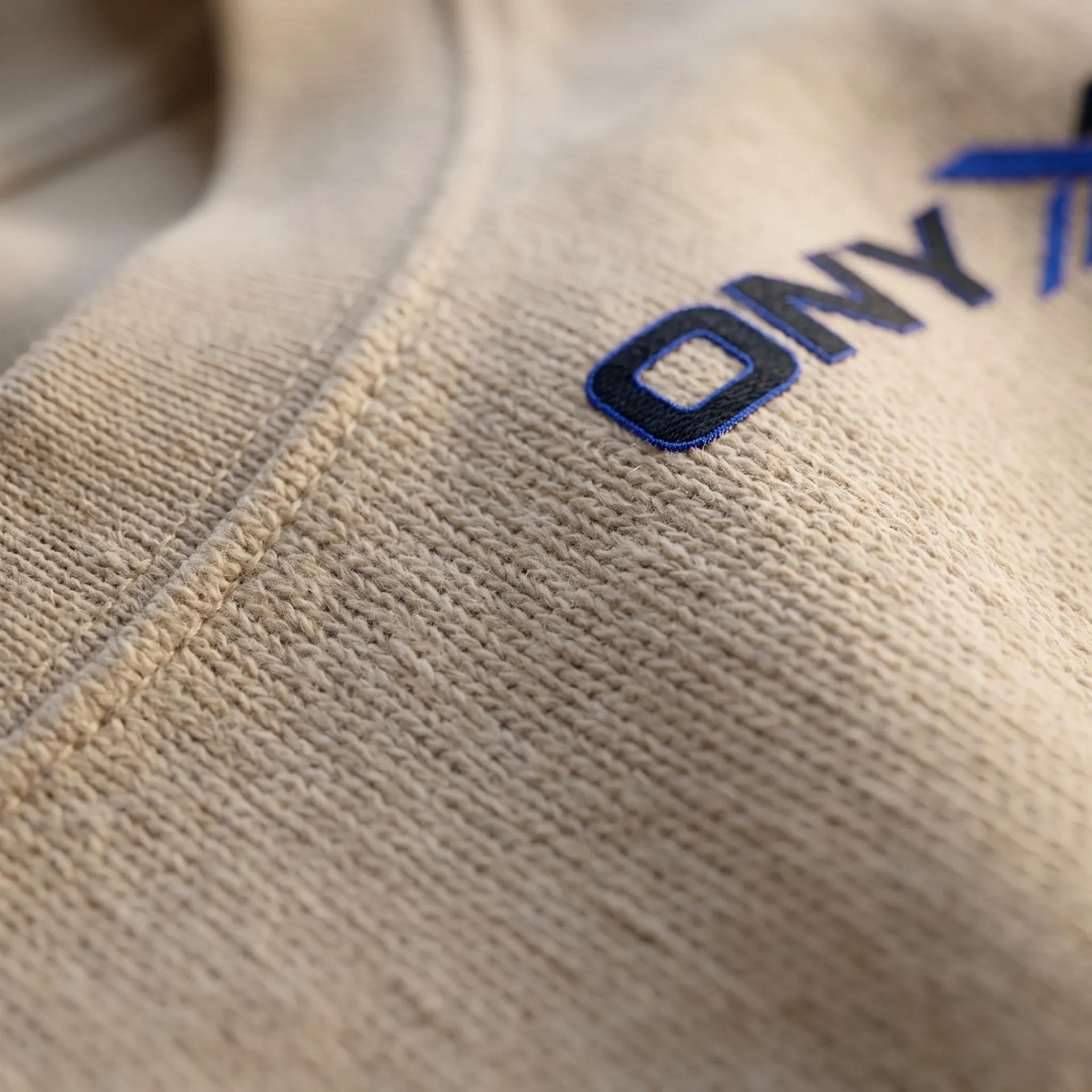 Macro detail of fabric, stitching and logo on the Oversized Heavyweight Tee